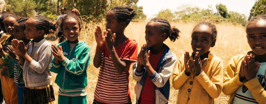 Kinder stehen in einer Reihe und klatschen in die Hände