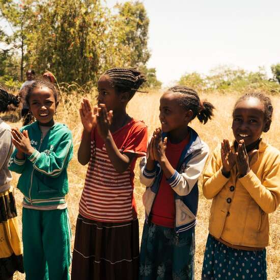 Kinder stehen in einer Reihe und klatschen in die Hände