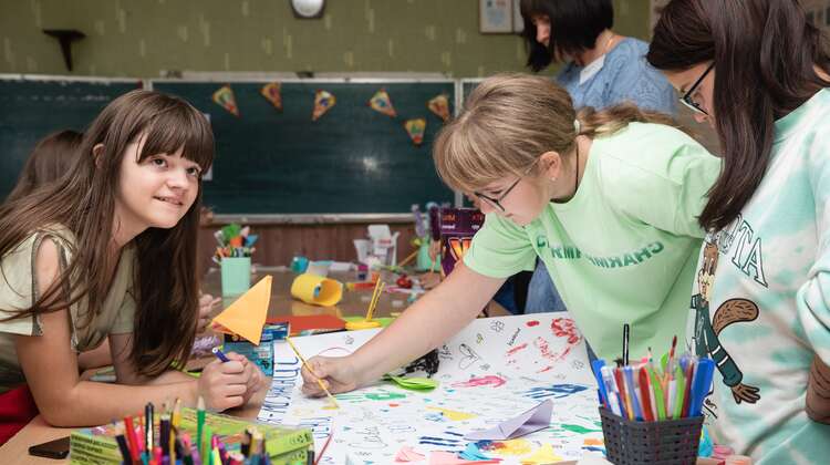 Children in a classroom painting together on a large picture