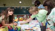 Children in a classroom painting together on a large picture