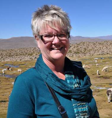 Mitarbeiterin Ulla Förster in Peru vor einer Herde Alpakas. 