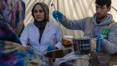 Eine Frau und ein Mann stehen in einem Zelt und verteilen Mahlzeiten.