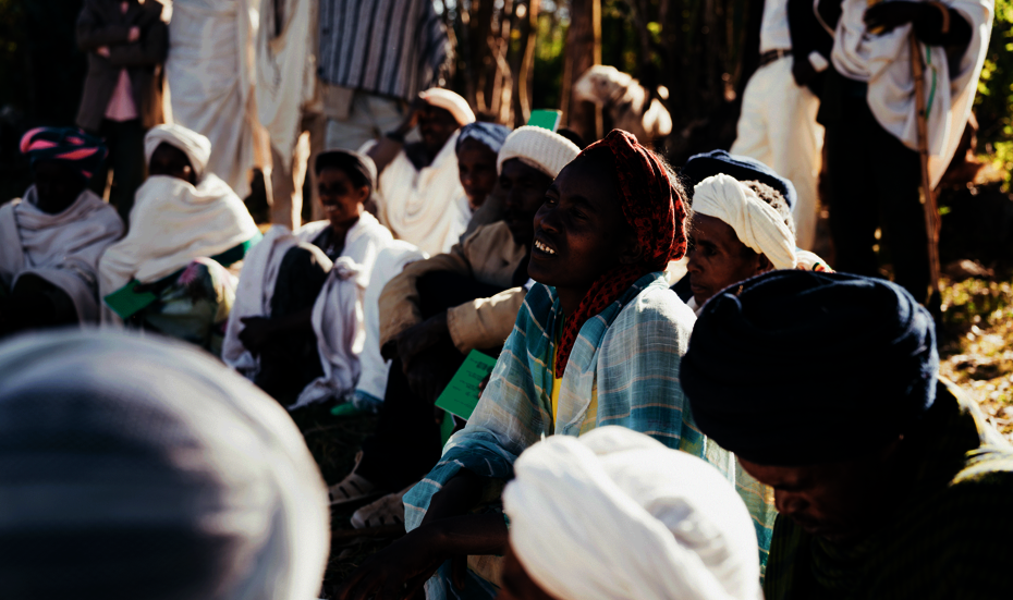 Frauen und Männer sitzen während eines Workshops auf dem Boden und hören zu.