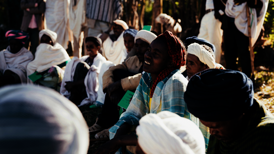 Frauen und Männer sitzen während eines Workshops auf dem Boden und hören zu.