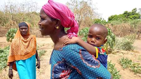 Eine Frau mit ihrem Baby auf dem Rücken.