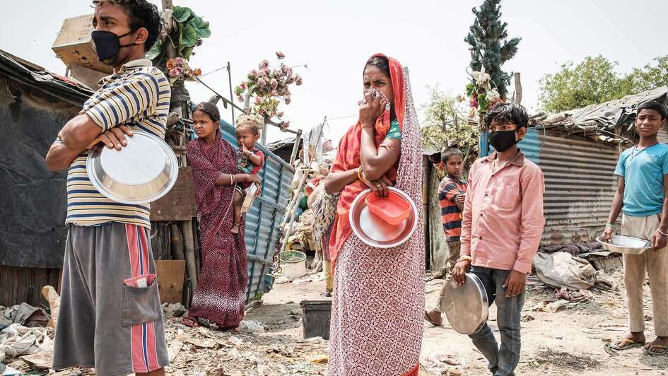 Ein Mann, eine Frau und zwei Jungen mit Masken stehe in einer Schlange.