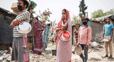Ein Mann, eine Frau und zwei Jungen mit Masken stehe in einer Schlange.