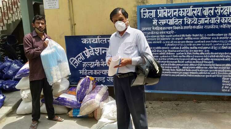 Zwei Männer mit Schutzmaske verteilen Hilfsgüter.