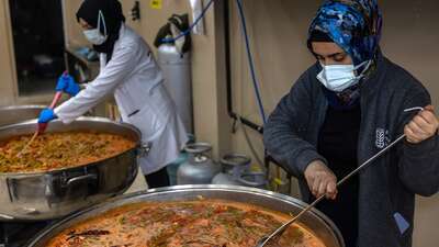 Zwei Frauen bereiten in großen Kochtöpfen Mahlzeiten für Erdbebenopfer zu.