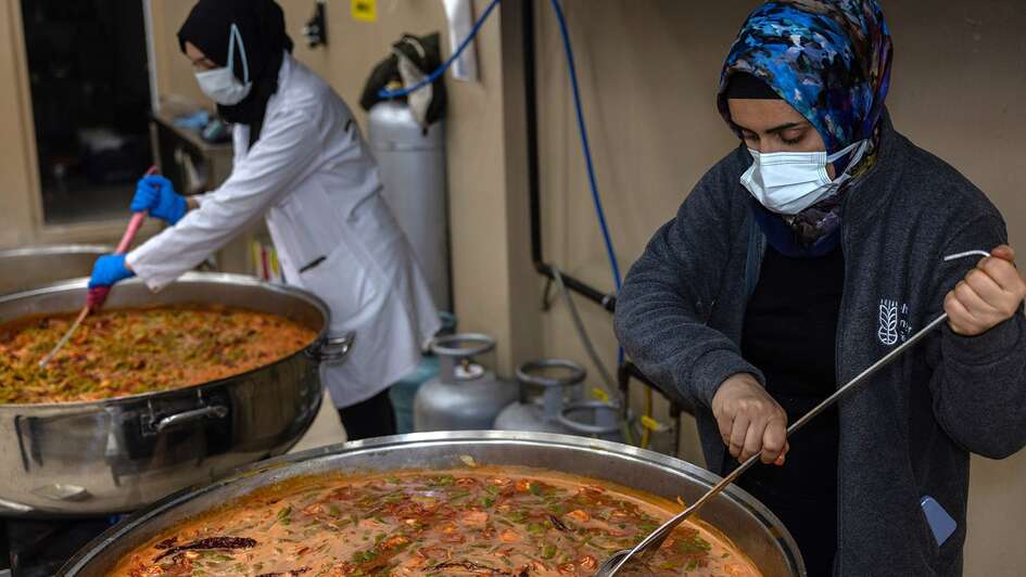 Zwei Frauen bereiten in großen Kochtöpfen Mahlzeiten für Erdbebenopfer zu.