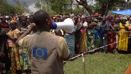 A man with a megaphone addresses a group of people