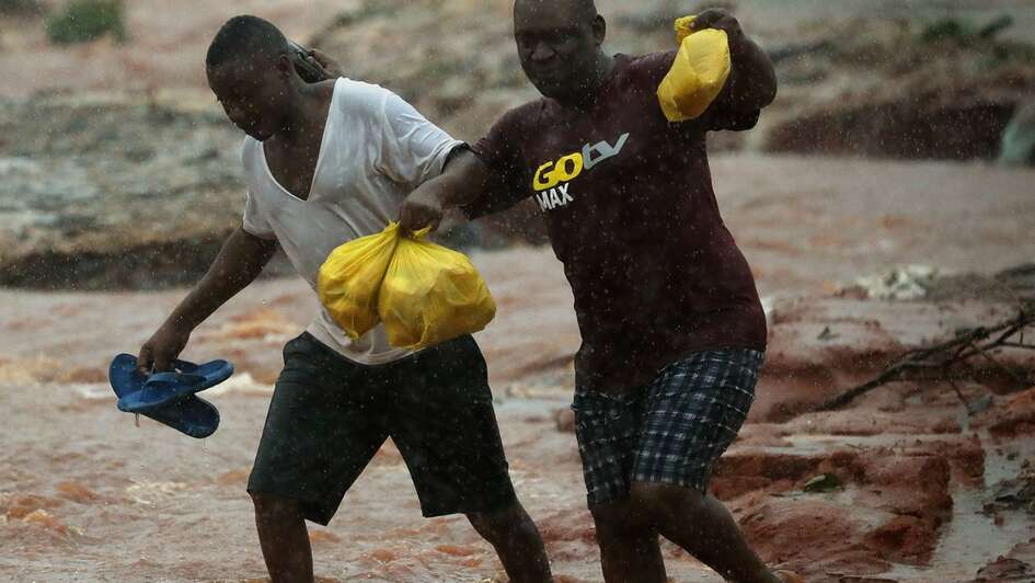 Two men walking through a flooded area