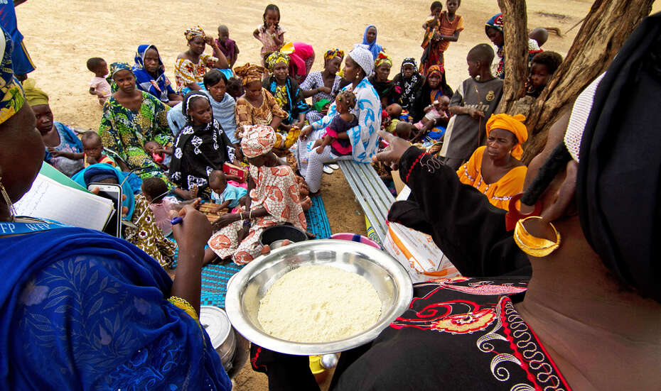 Two trainers are standing in front of a sitting group of women.