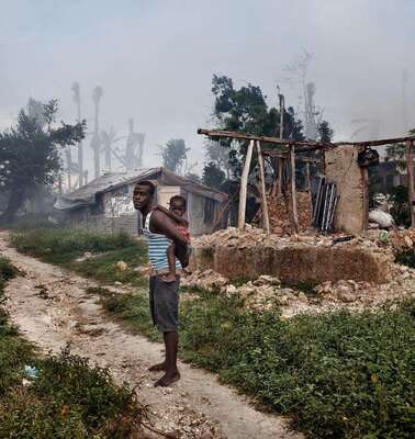 A man with his daughter in front of the remains of a house in Grand Anse.