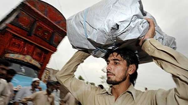 Ein Flüchtling transportiert seinen Besitz auf dem Kopf.
