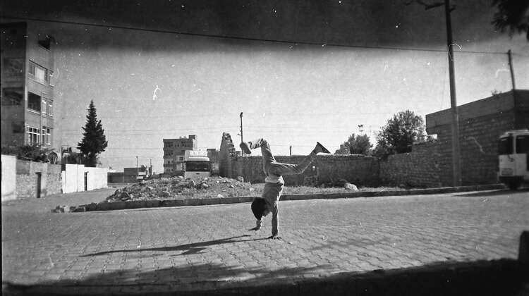 A child doing a handstand in front of rubble