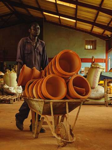 Finished fired clay filters are transported in a wheelbarrow.