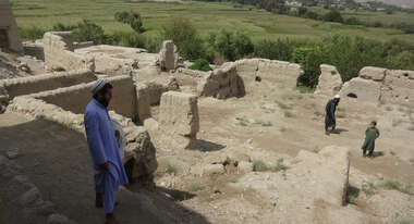Ein Mann und zwei weitere Personen in weiterer Entfernung stehen in einer Ruine.