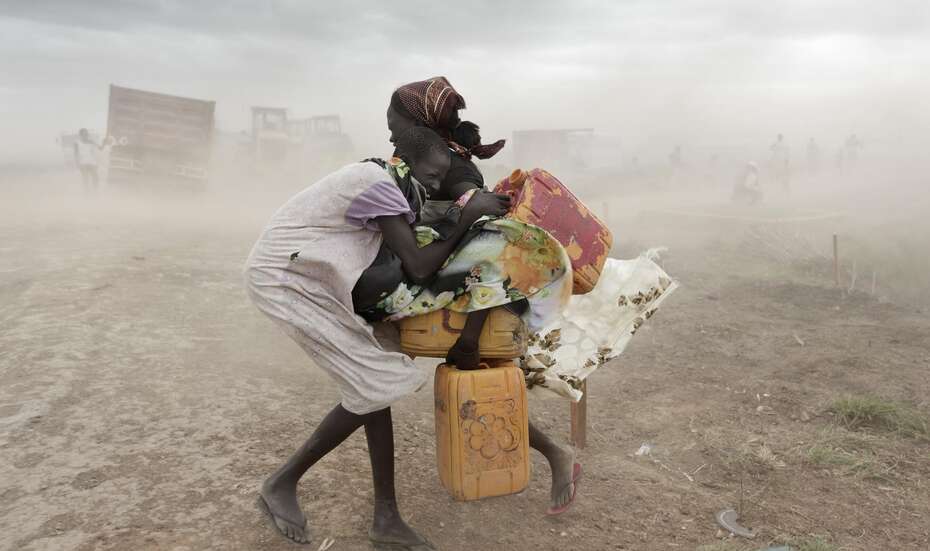 Two girls protecting themselves from a storm in a refugee camp