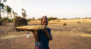 Eine Frau hält ein eine große Platte mit geerntetem Getreide in der Hand