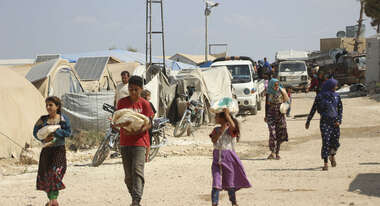 Refugees carry bags of bread in a refugee camp