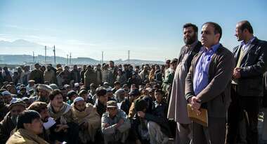 Flüchtlinge in Winterkleidung warten auf die Verteilung von Haushaltsgütern