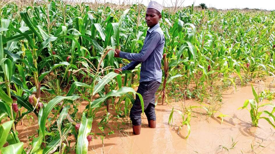 Ein Mann steht auf einem überfluteten Feld im Wasser