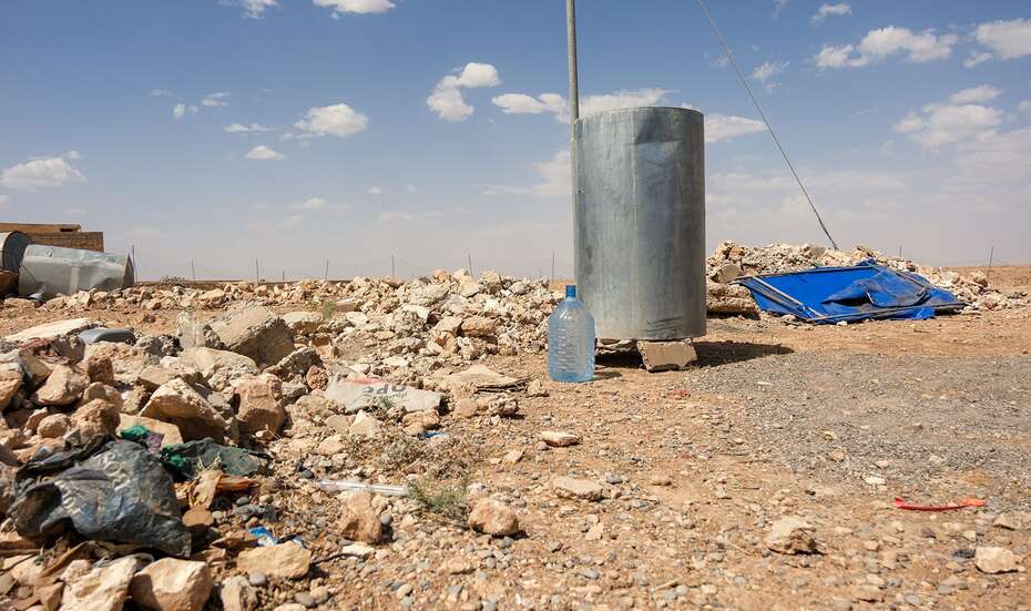 Metal tank in a barren landscape full of rubble.