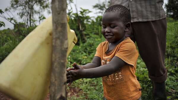 Ein Junge wäscht sich die Hände mit Hilfe eines Tippy Tap.