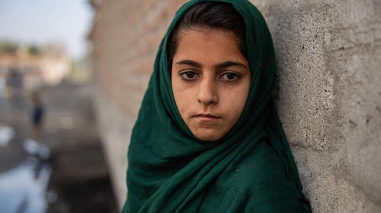 Ein Mädchen mit grünem Kopftuch schaut ernst in die Kamera.