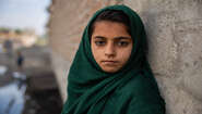 Ein Mädchen mit grünem Kopftuch schaut ernst in die Kamera.