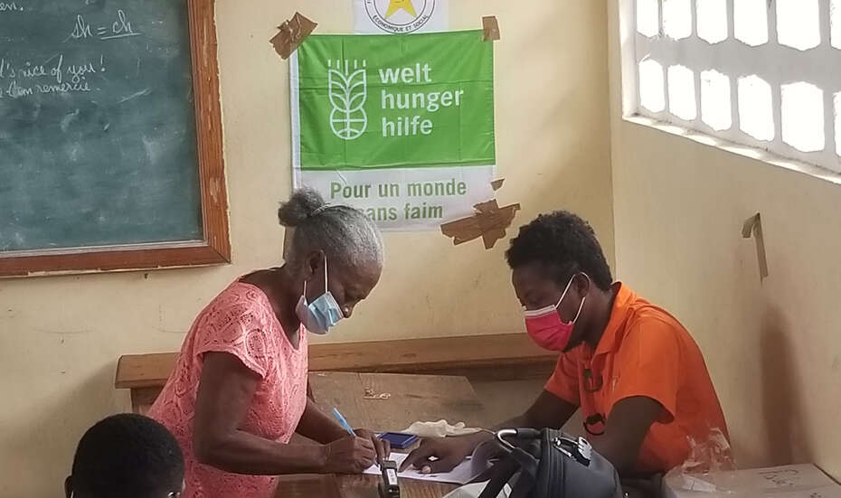 Eine Frau und ein Mann sitzen gemeinsam an einem Tisch und besprechen Hilfsmöglichkeiten nach dem Erdbeben, Haiti 2021.