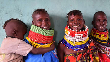 Kenyan women wearing traditional clothing smile towards the camera