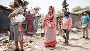 A man, a woman and two boys with masks are standing in a queue.