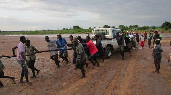 Several people towing a car that got stuck