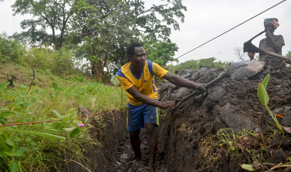Ein Mann steht in einem Graben und schaufelt Erde hinaus.