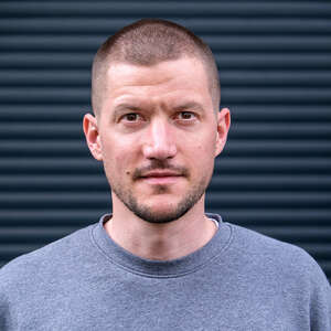 Porträtbild von Stefan Isbrecht. Er hat kurze Haare und trägt einen grauen Pullover.