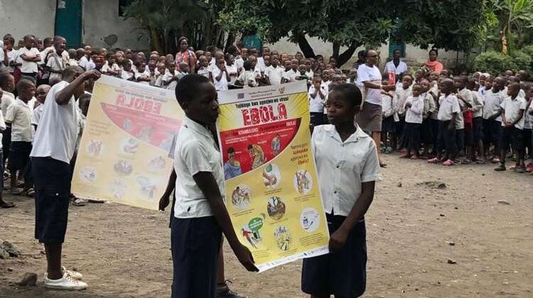 Schulkinder in der Nähe von Goma (D. R. Kongo) halten Informations-Plakate über die Gefahren, Ansteckungswege und Symptome von Ebola sowie über Präventionsmaßnahmen.