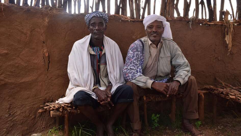 Two Ethopians sitting on chairs.