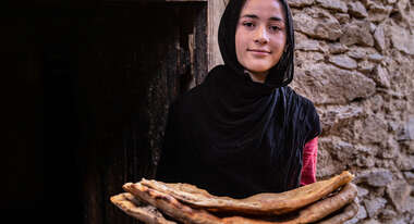 A smiling woman holding flat bread 