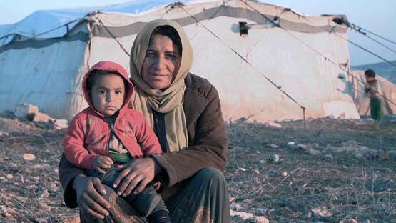 Winterhilfe in Syrien: Eine Mutter sitzt mit ihrem Kind auf der Erde