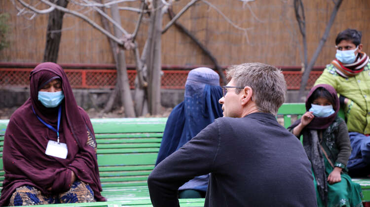 Verschleierte Frauen im Gespräch mit Welthungerhilfe Generalsekretär Mathias Mogge. Sie alle sitzen auf Bänken.