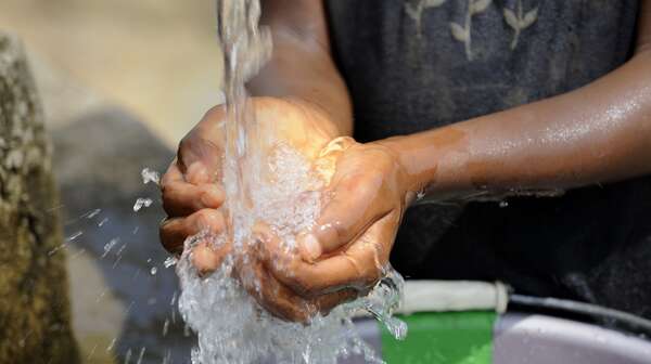 Kind schöpft Wasser mit den Händen