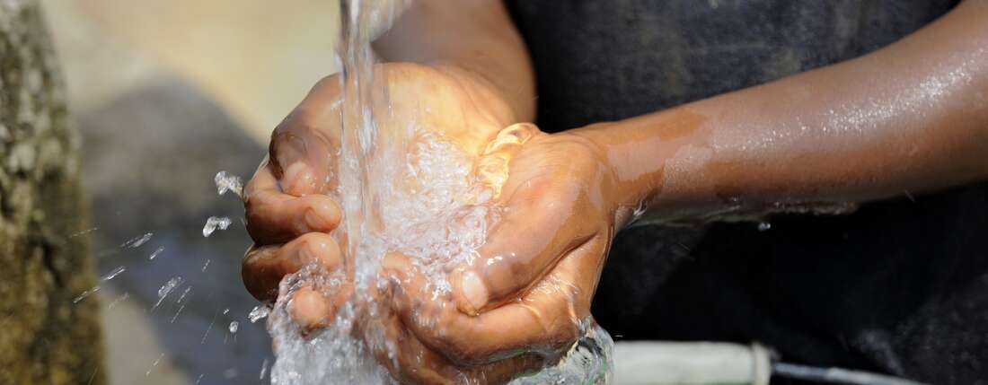 Kind schöpft Wasser mit den Händen