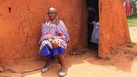 Massai Esther Sululi Makooi in front of cabin.