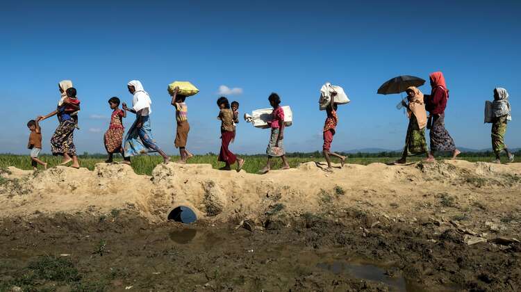 2017-rohingya-auf-der-flucht-fussmarsch-bangladesch_C_Daniel-Pilar-hires.jpg Frauen und Kinder tragen ihr Hab und Gut über einen schlammigen Weg