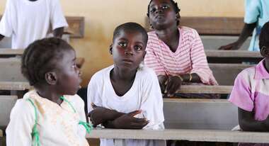 Kinder sitzen hintereinander in Schulbänken