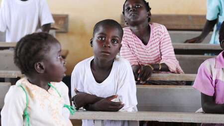 Kinder sitzen hintereinander in Schulbänken