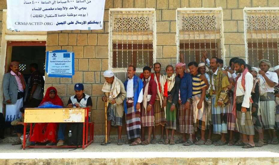 Menschen stehen bei einer Bargeldverteilung Schlange. 