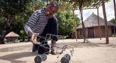 Ein Junge mit einem Spielzeugauto aus Draht 